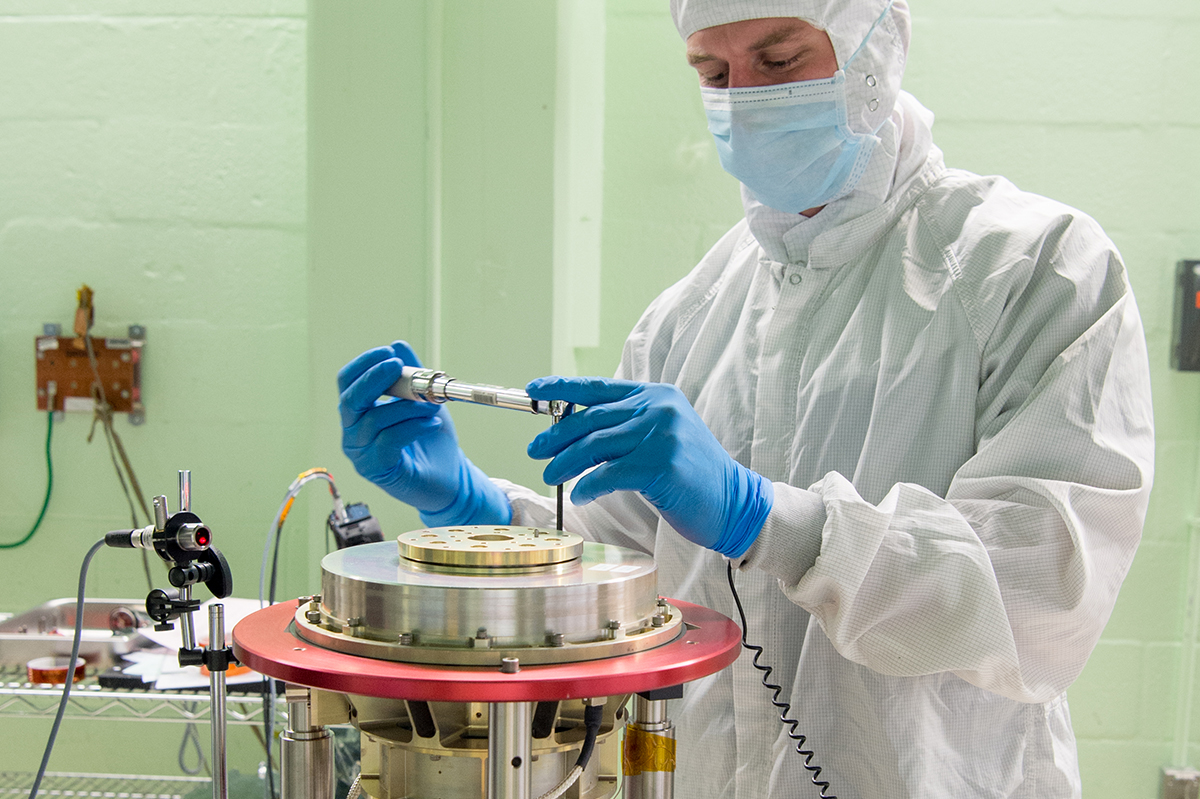 A NASA technician assembles the Half-Angle Mirror (HAM) mechanism in preparation for balancing activities.