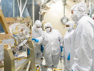 Blanket technicians discuss thermal templates on the Ocean Color Instrument Instrument Deck Structure (IDS) at Goddard Space Flight Center.