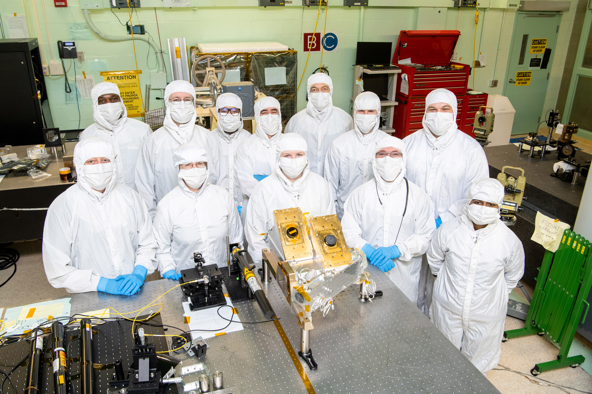 Members of the Ocean Color Instrument Main Optics Sub Bench (MOSB) integration team pose with the hardware prior to its integration onto the Main Optics Bench (MOB).