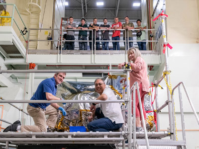 The Ocean Color Instrument mechanical team poses with the bagged instrument after successfully installing it onto the X-Axis (vertical) vibration shaker table. Credit: Mellos, Katherine