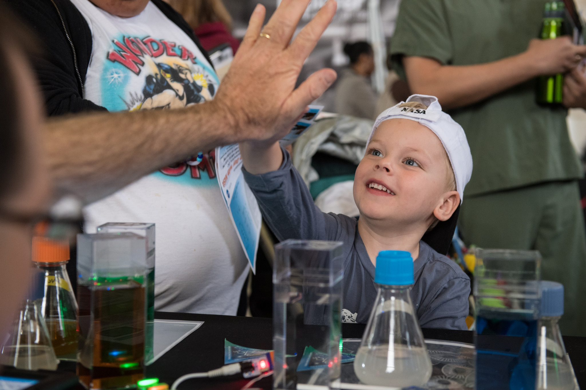 A visitor gives a high five after learning about phytoplankton at the PACE table at the Earth Day event at Union Station in Washington, D.C.