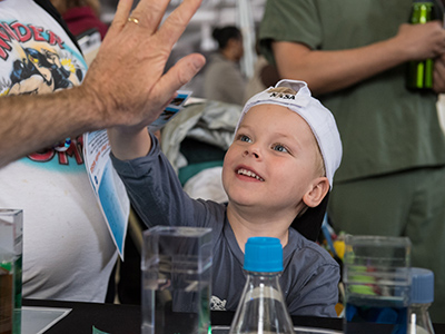 A visitor gives a high five after learning about phytoplankton at the PACE table at the Earth Day event at Union Station in Washington, D.C. Credit: Aubrey Gemignani (NASA)