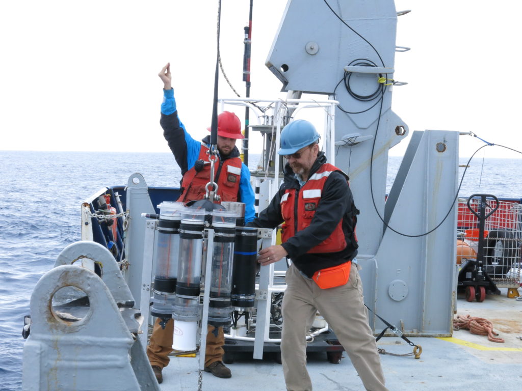 At right, Marine Chemist Ken Buesseler (WHOI) deploys a sediment trap from the R/V <em>Roger Revelle</em>.