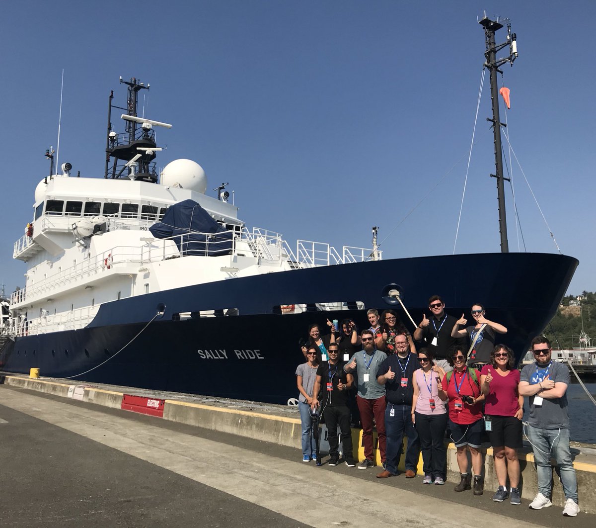 Participants from a NASA social media event pose by the R/V <em>Sally Ride</em> before it embarks on its August 2018 tour of the North Pacific.